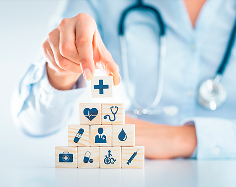 Profissional de saúde montando pirâmide com blocos ilustrando símbolos médicos.