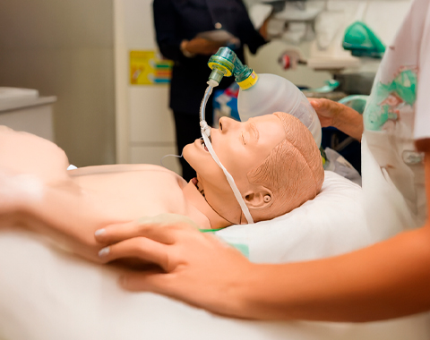 Treinamento de simulação médica com manequim para prática de ventilação assistida. Manequim médico em um ambiente hospitalar sendo utilizado para simulação de ventilação com máscara e tubo endotraqueal.